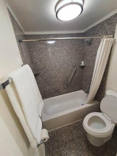 a bathroom with a toilet and a tub and a sink at Ocotillo Apartments & Hotel in Phoenix