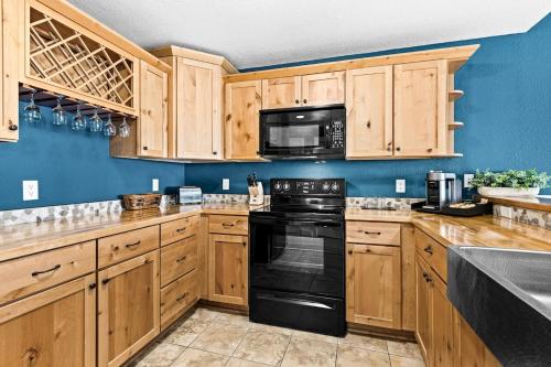 a kitchen with wooden cabinets and a black stove top oven at Breathtaking Lake Views 1BR King Suite, Kitchen & Heated Pools in Two Harbors
