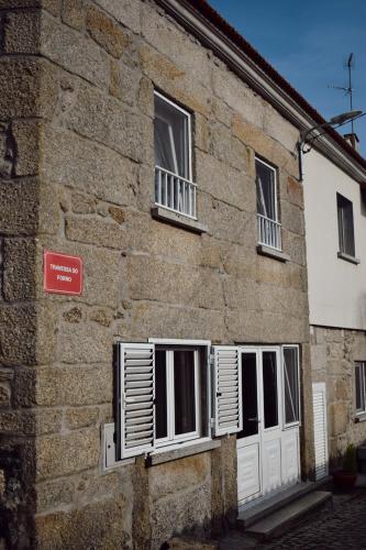 a brick building with two windows with white shutters at Casas Ti Flores in Sabugal