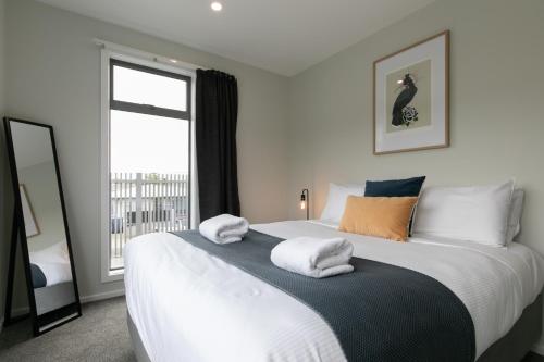 a bedroom with a large white bed with towels on it at Taradale Gem in Napier