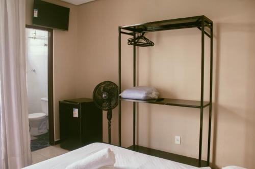 een slaapkamer met een bed en een badkamer met een ventilator bij Kitnet no centro de Betim in Betim