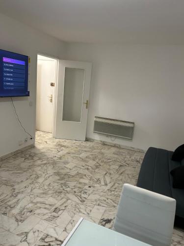an office room with a marble floor and a television at Deux pièces au centre-ville proche des plages et centres commerciaux in Saint-Laurent-du-Var