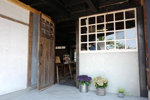 an open door with a window and some flowers at 海と鉄 1日1組限定の宿 in Sukumo