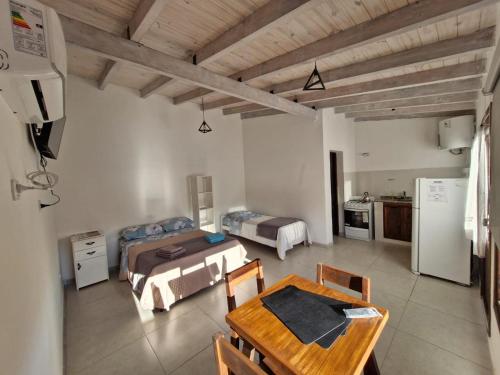 a room with two beds and a table and a kitchen at Vista Los Andes - APART TURISTICOS TREVELIN in Trevelin