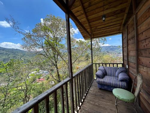 Un balcón con una silla azul y una vista. en Cabañas la esperancita, en Guatuso
