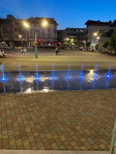 a fountain with blue lights in a square at night at Apartments & Rooms Fountain in Bihać