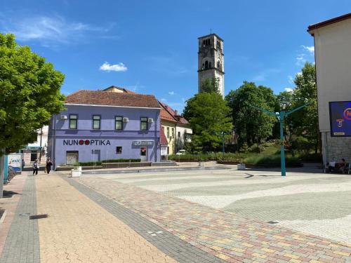 a street in a town with a building and a tower at Apartments & Rooms Fountain in Bihać