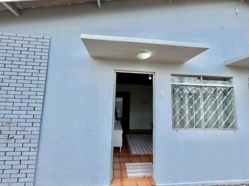 a white house with a blue door and a window at Casa em Condomínio no Centro de Ponta Porã in Ponta Porã