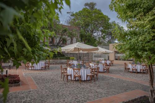 an outdoor patio with tables and chairs and umbrellas at Holiday Inn Tlaxcala by IHG in Tlaxcala de Xicohténcatl