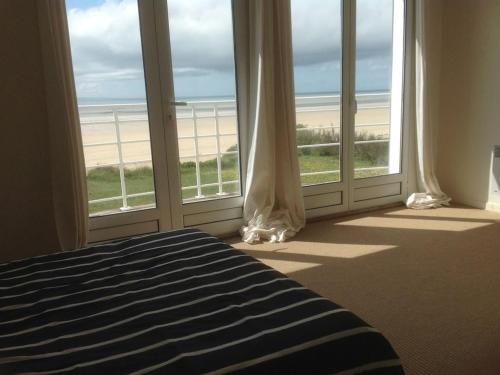 une chambre avec un lit et une vue sur la plage dans l'établissement Beautiful fisherman's cottage rebuilt in 1940, à Denneville
