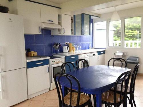 une cuisine avec une table et des chaises ainsi qu'une cuisine bleue dans l'établissement Beautiful fisherman's cottage rebuilt in 1940, à Denneville
