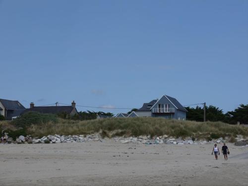 2 personnes marchant sur une plage avec des maisons en arrière-plan dans l'établissement Beautiful fisherman's cottage rebuilt in 1940, à Denneville
