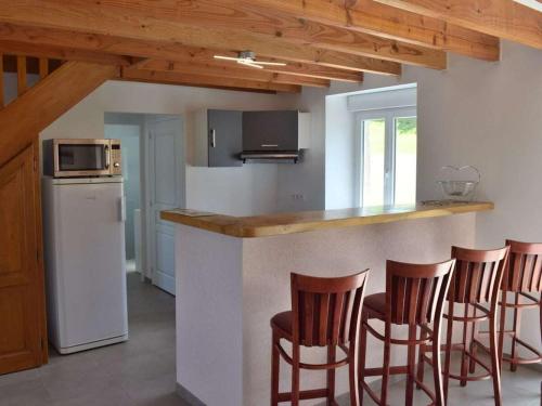 une cuisine avec quatre tabourets de bar et un comptoir dans l'établissement Holiday cottage with 2 bedrooms, à Saint-Lo-dʼOurville