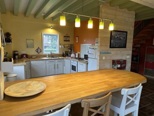 une cuisine avec une grande table en bois et des chaises dans l'établissement The Red House near the beach, à Denneville-Plage