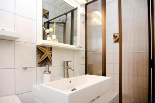 a white bathroom with a sink and a mirror at Reihenhaus Land and Sea in Büsum in Büsum