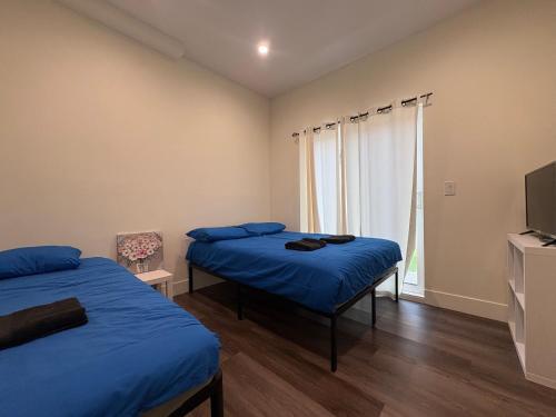a bedroom with two beds and a tv and a window at Blue Stay Walk to BMO Stadium and USC in Los Angeles