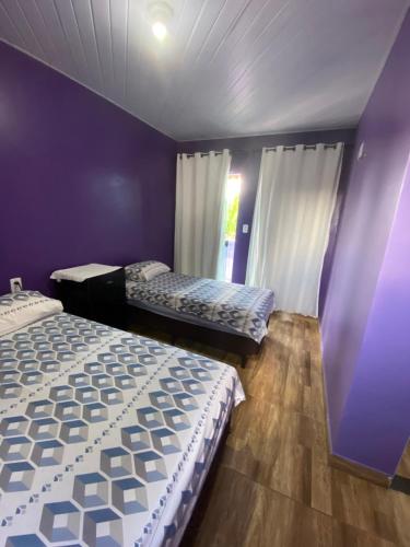 a bedroom with two beds and a purple wall at Pousada hotel trevo do Atalaia in Salinópolis