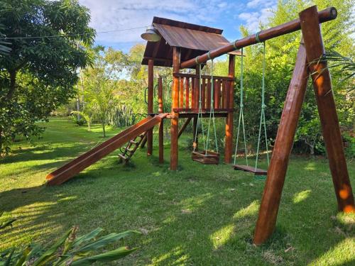 a wooden playground with a slide in the grass at Quinta das Palmeiras Area 2 in Montes Claros