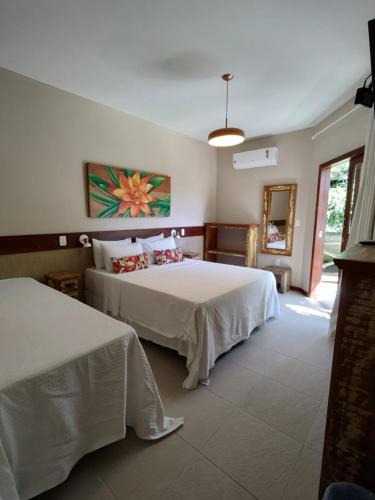 a bedroom with two beds and a mirror at Pousada Caiçara in Abraão