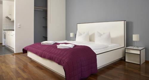 a bedroom with a large bed with a purple blanket at Karlito Apartmenthaus in Berlin