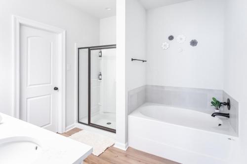 a white bathroom with a bath tub and a sink at La Vida Loca Stay in Baton Rouge near LSU - BC1011 in Baton Rouge