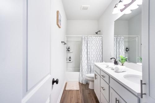 a white bathroom with a sink and a toilet at La Vida Loca Stay in Baton Rouge near LSU - BC1011 in Baton Rouge