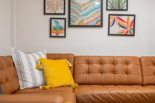 a brown leather couch sitting in a living room with paintings at Couples Retreat with Hot Tub, Beach Cruisers, Spa Bath in Kill Devil Hills