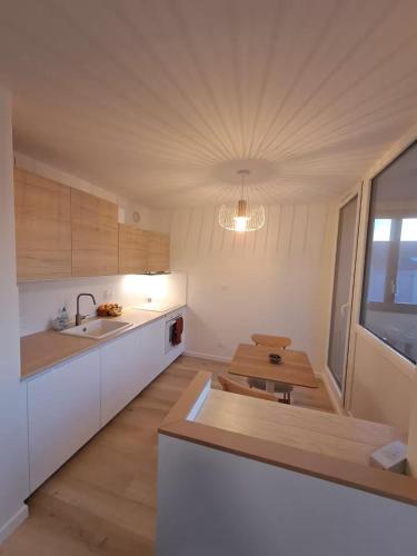 une cuisine avec des armoires blanches et une table en bois dans l'établissement Le Studio Lumière - Balcony - 5min Part-Dieu, à Lyon