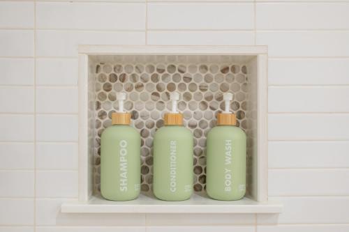three green bottles sitting on a shelf in a bathroom at Couples Retreat with Hot Tub, Beach Cruisers, Spa Bath in Kill Devil Hills