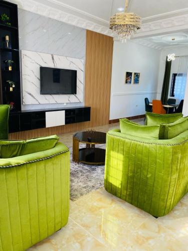 a living room with green chairs and a flat screen tv at DE Bolonia Lodge in Limbe