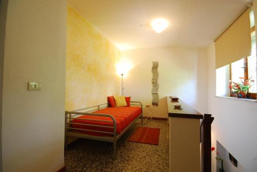 niewielka sypialnia z łóżkiem z pomarańczową pościelą w obiekcie Casina w mieście Gaiole in Chianti