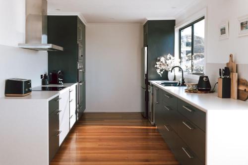 a kitchen with green cabinets and a wooden floor at Omaru Beach House in Scamander