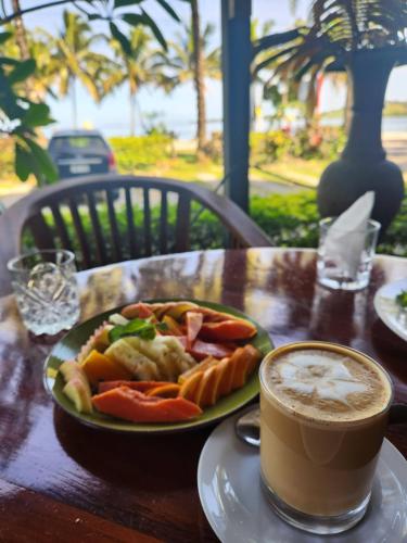 a plate of food on a table with a cup of coffee at Ramada Suites By Wyndham Seafront Coral Coast in Korotogo