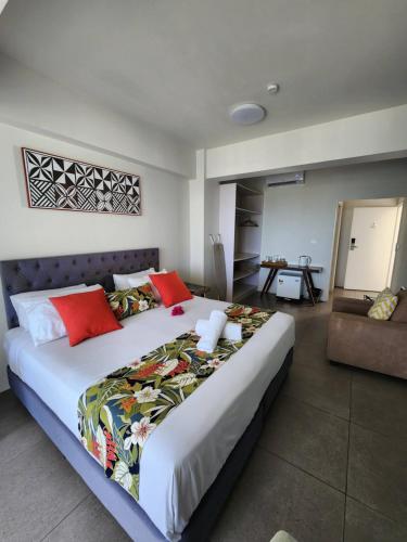a bedroom with a large bed with red pillows at Ramada Suites By Wyndham Seafront Coral Coast in Korotogo