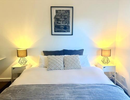 a bedroom with a white bed with two lamps at Welcome to The Roy - Family home close to airport and train! in Melbourne