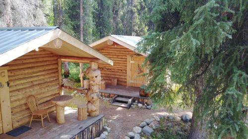 a cabin with a wooden deck and a table and chairs at Carlo Creek Cabins in McKinley Park