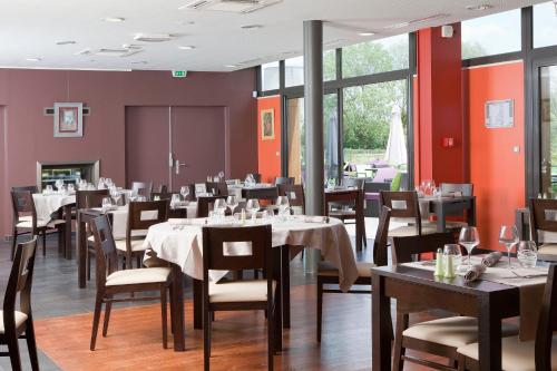 une salle à manger avec tables, chaises et fenêtres dans l'établissement Logis Hôtel Terre de Loire, à Belleville-sur-Loire