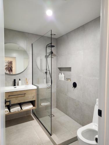 a bathroom with a shower and a sink and a toilet at Rooftop Apartment in Raglan
