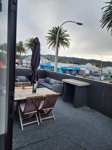 a patio with a table and chairs and a umbrella at Rooftop Apartment in Raglan