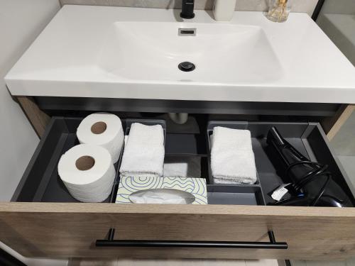 a drawer under a sink with toilet paper and towels at Rooftop Apartment in Raglan