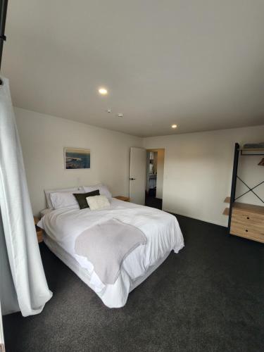 a bedroom with a large bed with white sheets at Rooftop Apartment in Raglan