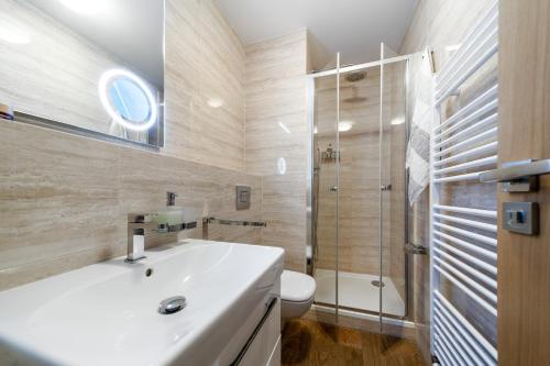 a bathroom with a white sink and a shower at Anenský Apartmán C303 s wellness , O2 TV a stabilní rychlou WIFI, s možností dokoupení bufetových snídaní a s možností dokoupení masáží in Harrachov