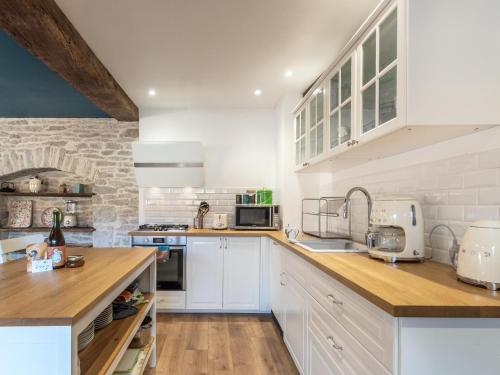 une cuisine avec des placards blancs et un mur en briques dans l'établissement Maison rénovée au bord de l'Ognon avec grand jardin et plage privée - FR-1-583-395, à Cenans