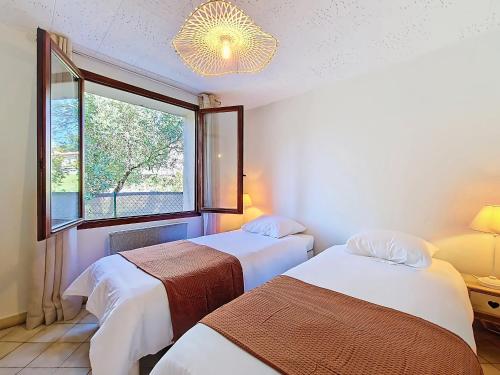 two beds in a room with a window at Rez de villa de charme à Montauroux près du lac Saint-Cassien, 2 chambres, jardin privatif - FR-1-779-16 in Montauroux