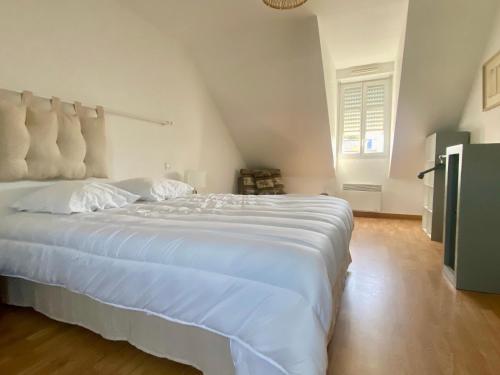 une chambre avec un grand lit avec des draps blancs dans l'établissement Maison rénovée proche du bourg avec terrasse et jardin - FR-1-813-26, à Groix