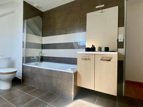 une salle de bain avec baignoire et toilettes dans l'établissement Maison rénovée proche du bourg avec terrasse et jardin - FR-1-813-26, à Groix