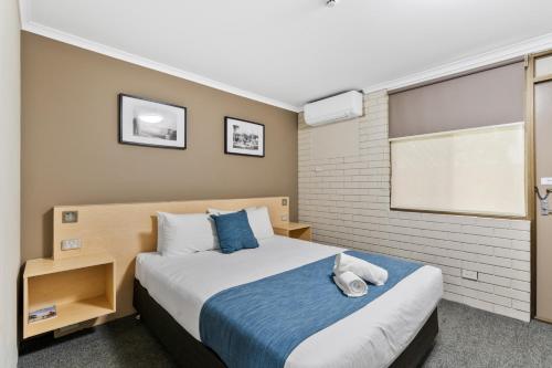a bedroom with a bed with a blue blanket at Morayfield Tavern in Morayfield