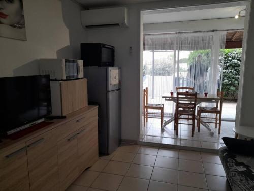 une cuisine avec une télévision et une table avec des chaises dans l'établissement Appartement 2P avec Clim, Terrasse et Parking, Le Barcarès - FR-1-782-76, au Barcarès