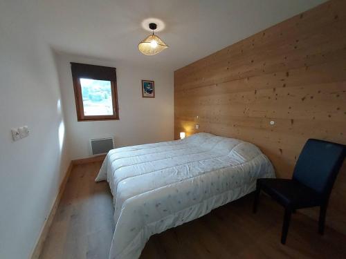 une chambre avec un lit et une chaise dedans dans l'établissement Appartement cosy 6 pers, accès pistes, parking inclus - FR-1-356-536, à Valmorel