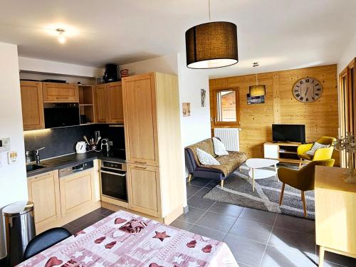 une cuisine avec des placards en bois et un salon dans l'établissement Appartement lumineux, centre proche, terrasse, parking - FR-1-598-190, aux Gets